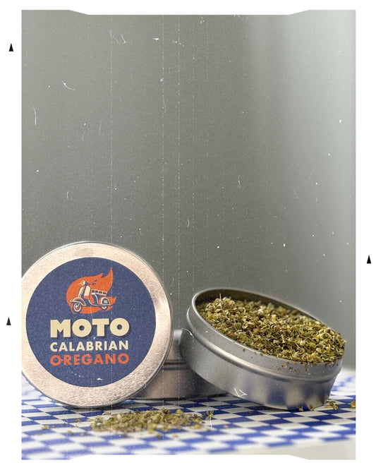 MOTO Calabrian Oregano tin with open lid showing oregano on a checkered surface.