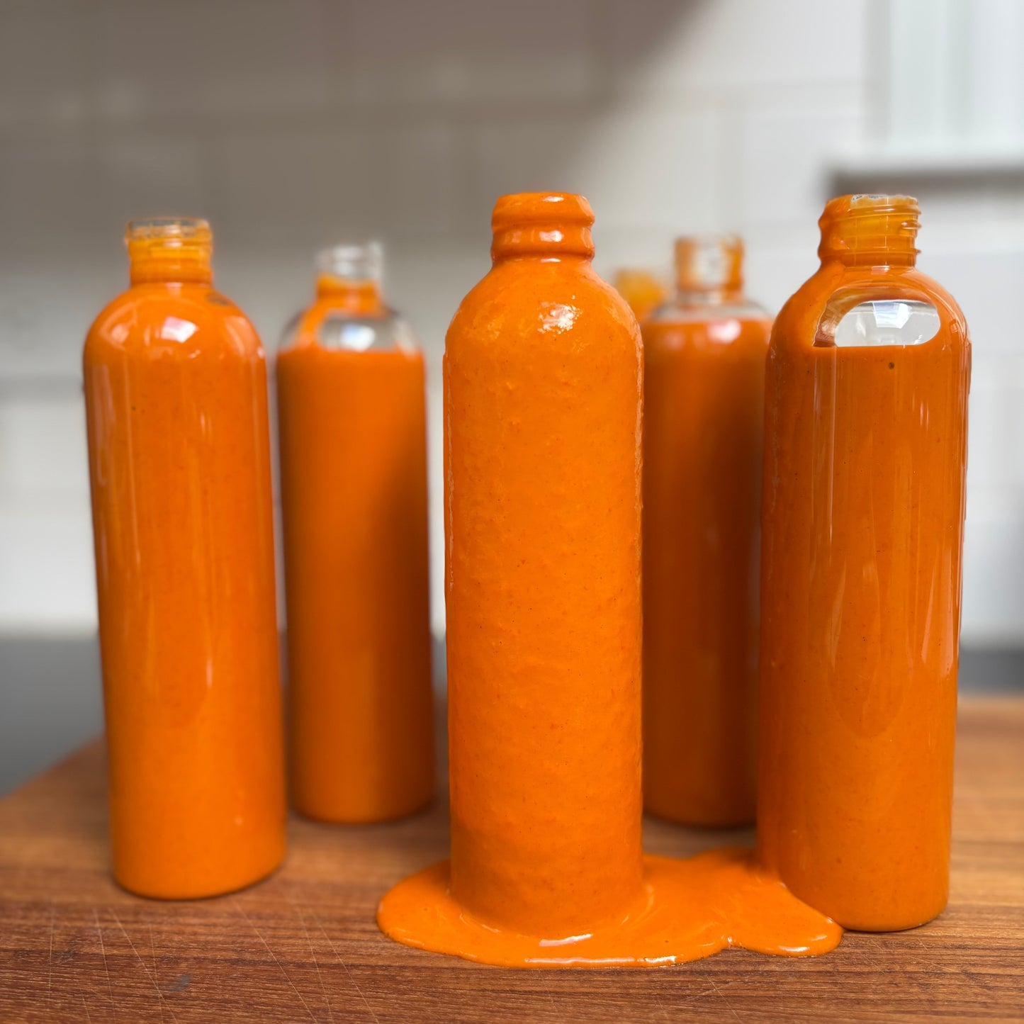 Set of orange bottles with one bottle spilling its contents on a wooden surface.