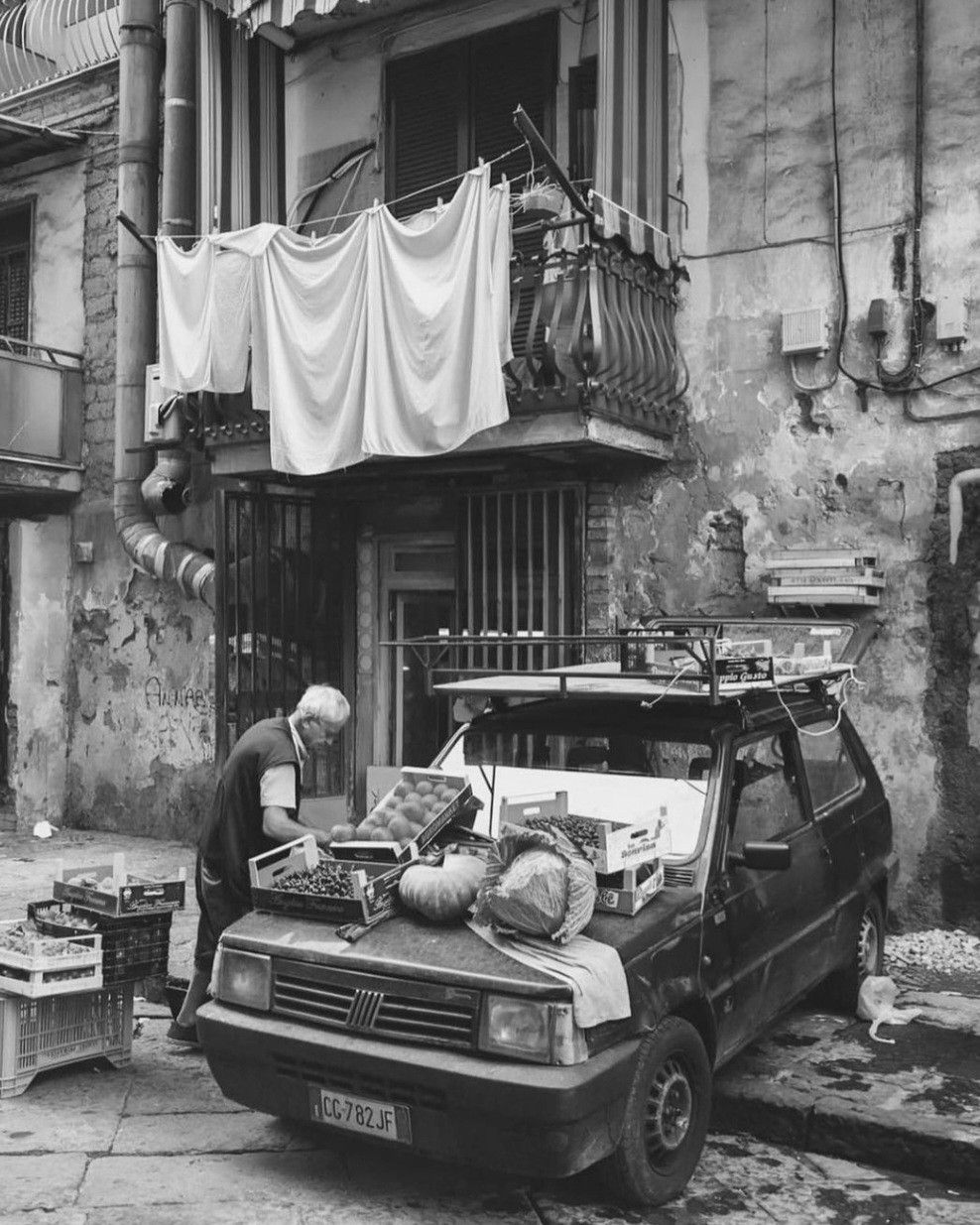 Vintage car parked on an Italian street with an old building and hanging laundry in the background
