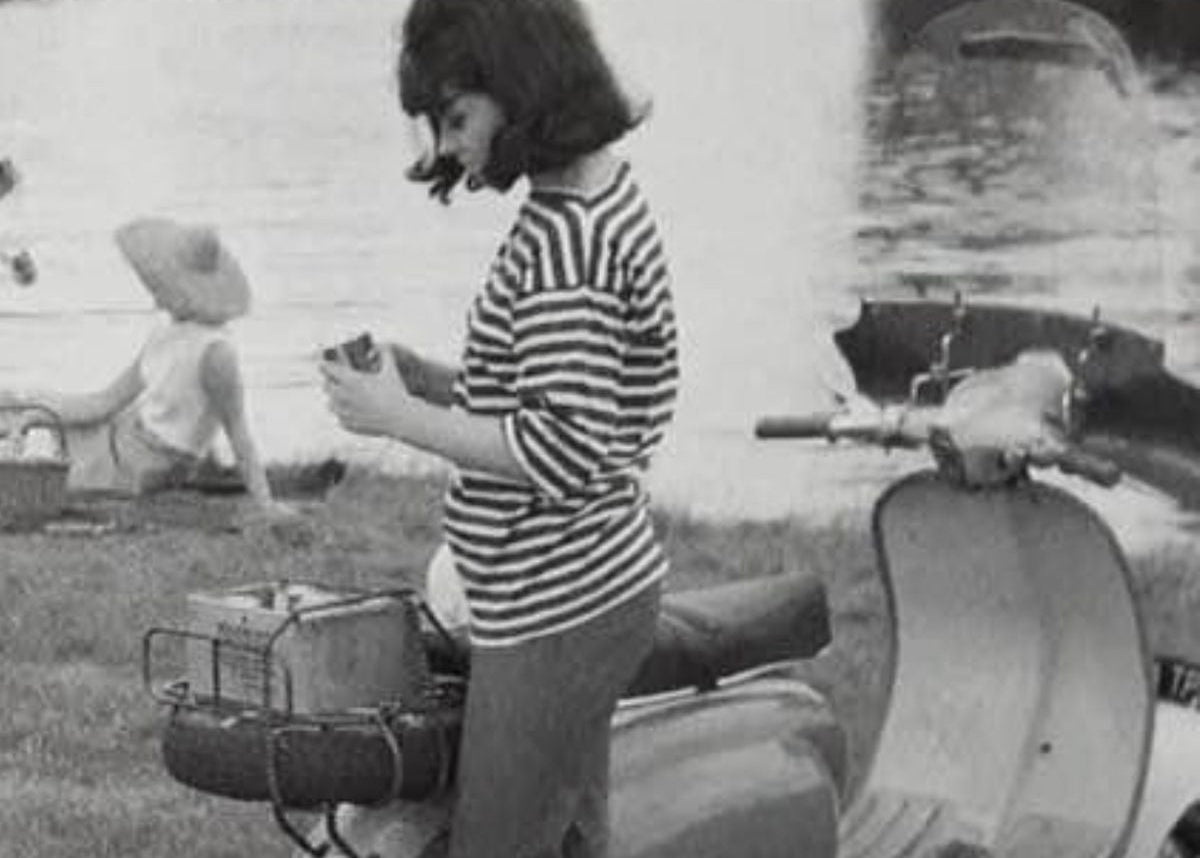 Vintage black and white photo of a woman with a striped shirt and an Italian scooter