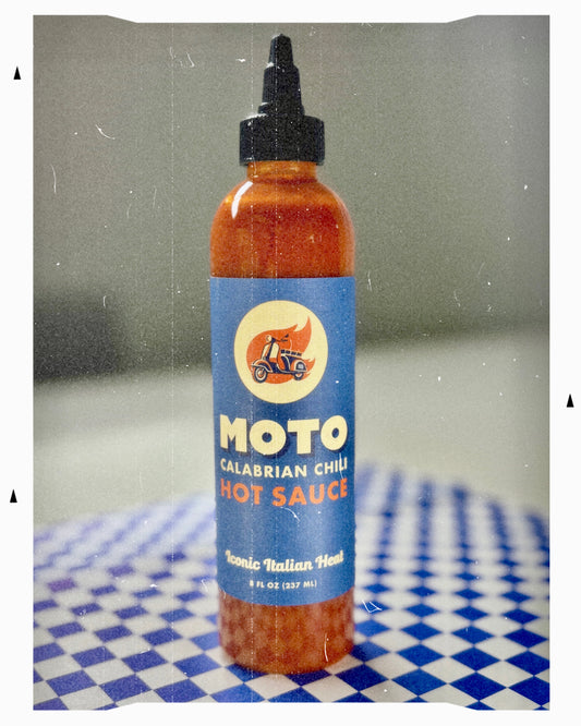 Bottle of Moto Calabrian Chili Hot Sauce on a checkered tablecloth