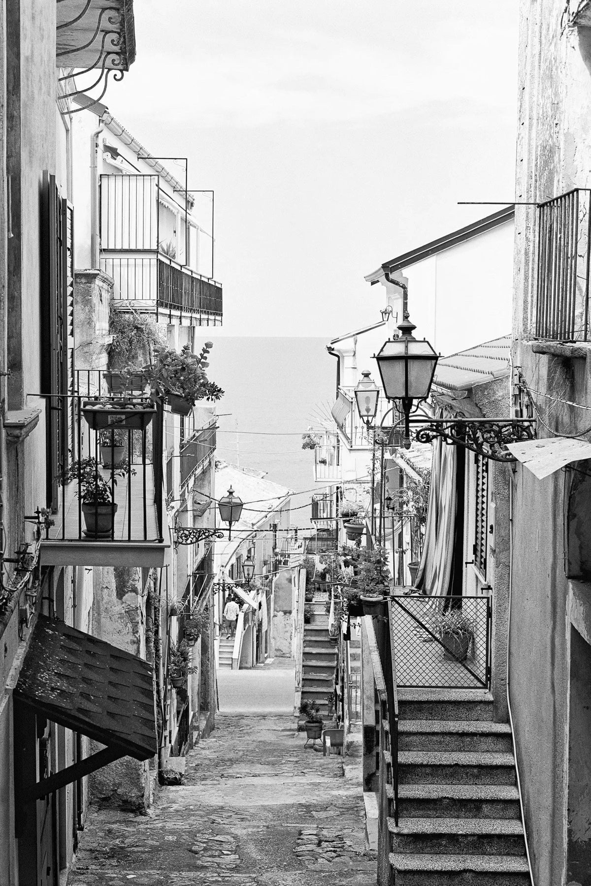 Black and white photo of an alley in Tropea Calabria Italy leading to the ocean.